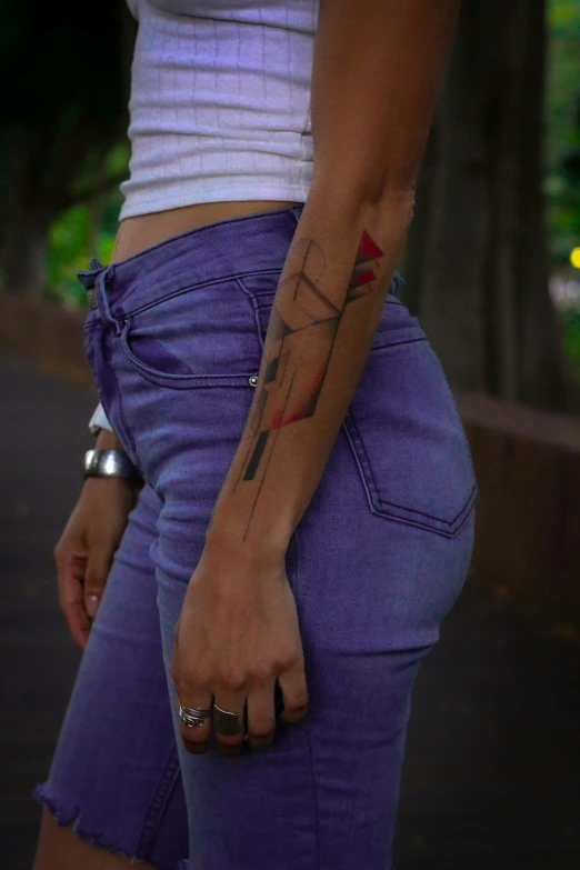 a girl's hand holding onto her purple jean pants