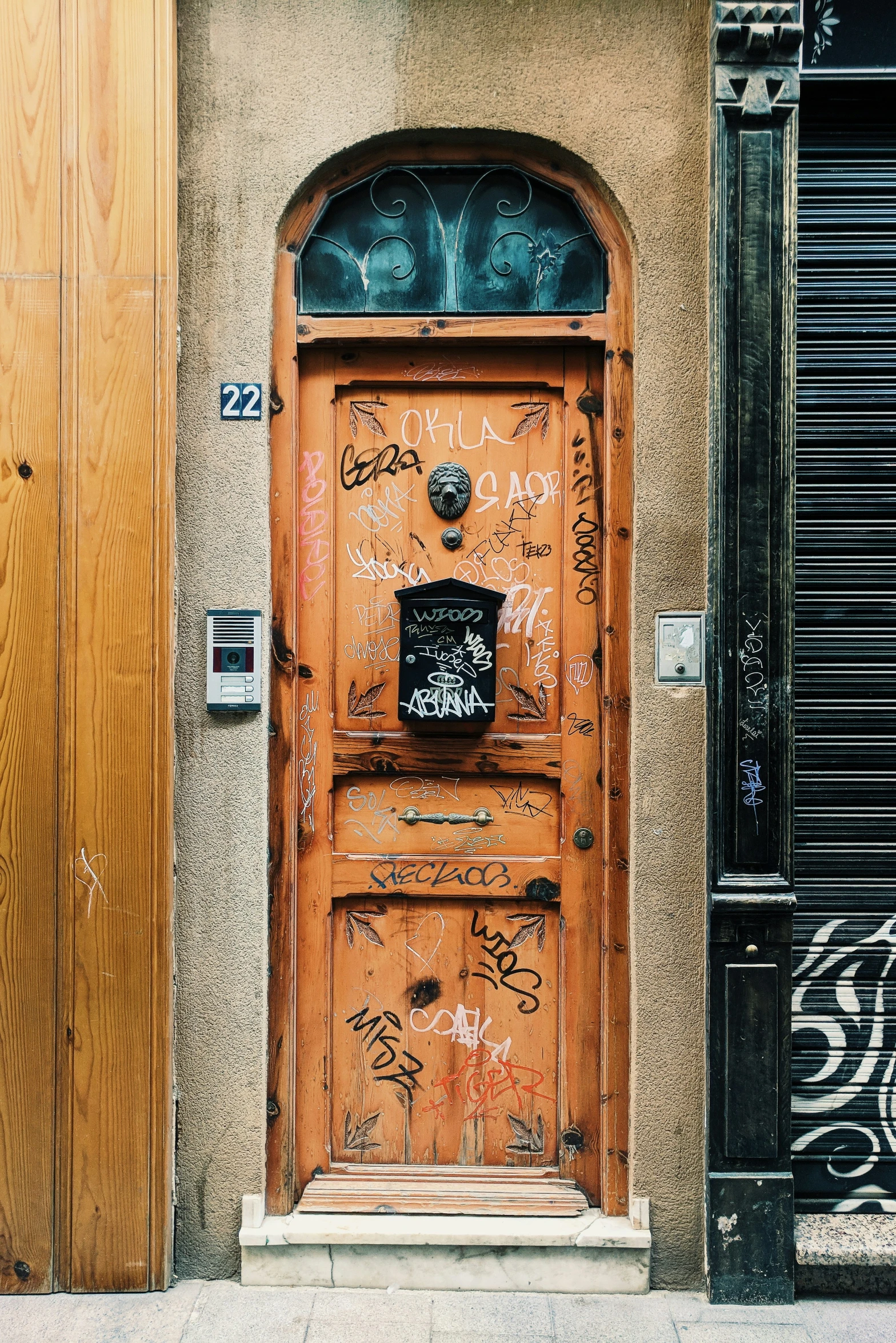 a brown door with graffiti and a clock is pictured