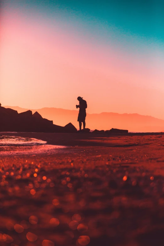 a person holding an umbrella standing on the edge of a beach