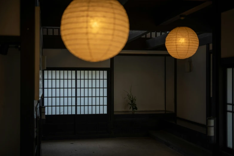 two lanterns are in an empty room, one hanging above the other