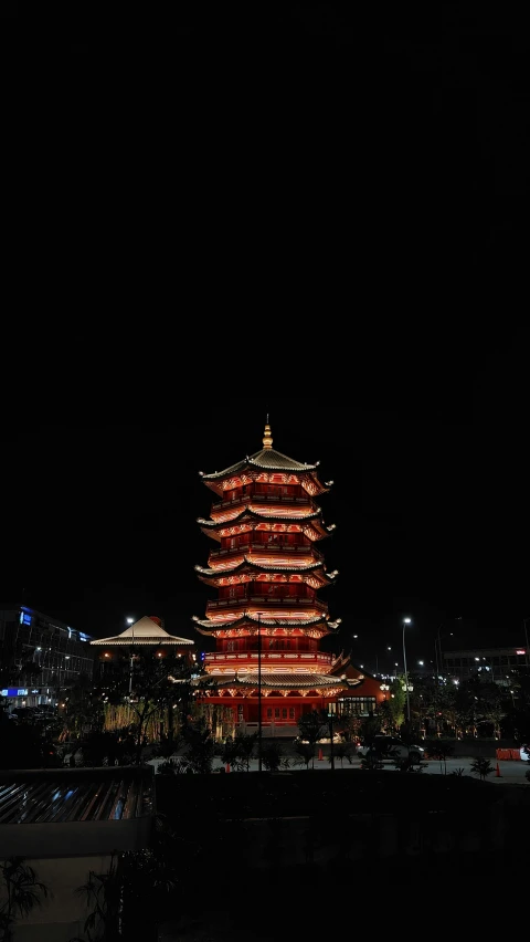 a chinese style pagoda with buildings lit up in the background