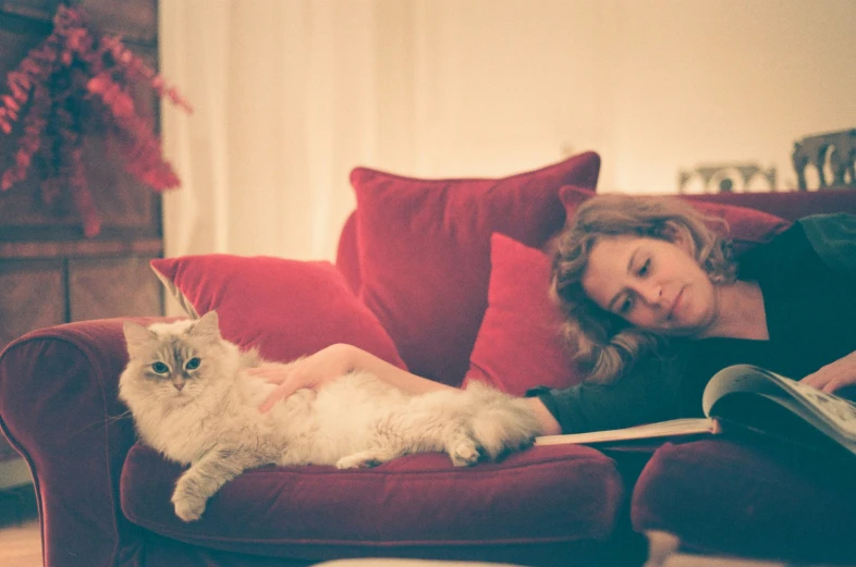 a woman is sitting on a couch with a large white cat