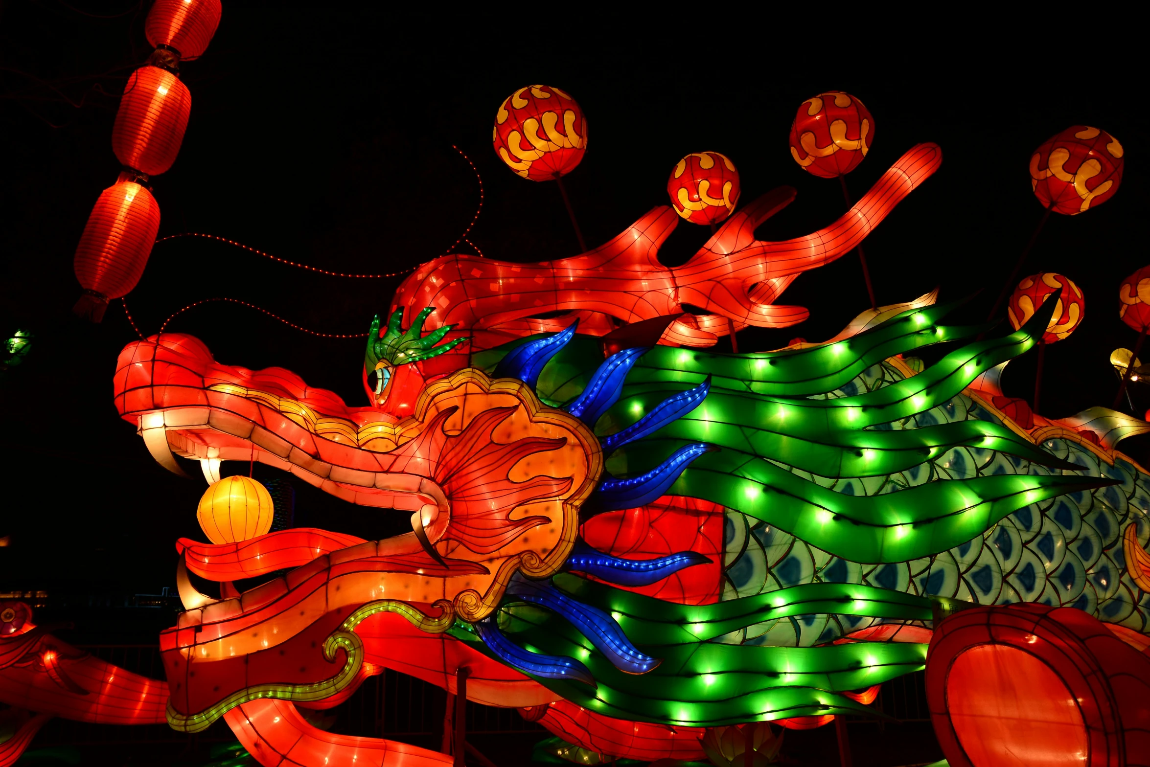 red dragon shaped lanterns glow at night, on dark background