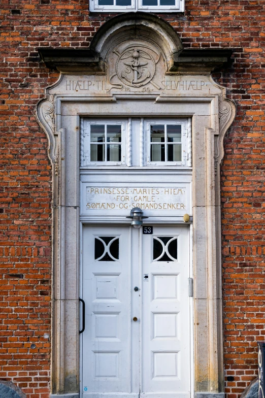 an old door on a brick building has carvings and signs