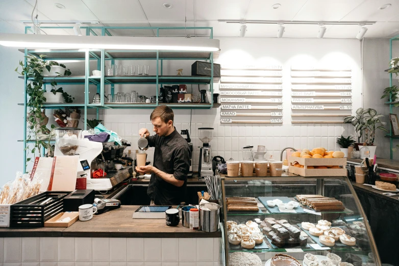 a man stands behind a bakery counter making donuts