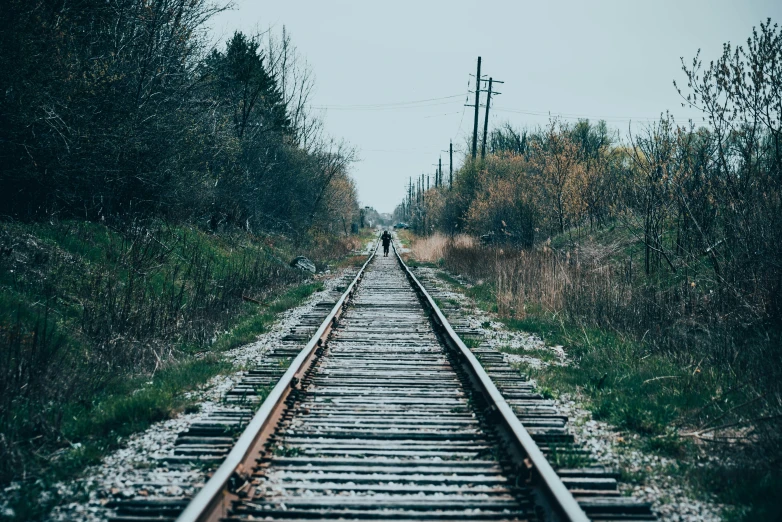 a person walking down the railroad tracks into the distance