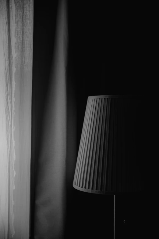 a lamp with a black shade and curtain in the background