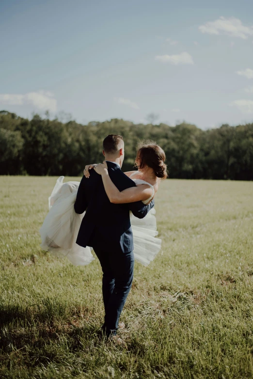 a bride and groom dancing in the grass