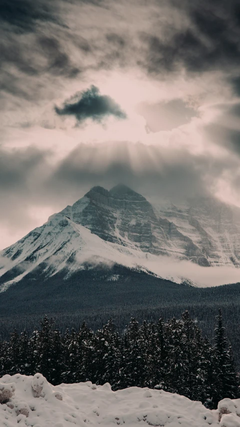 an almost cloudy day is seen over a snow covered mountain