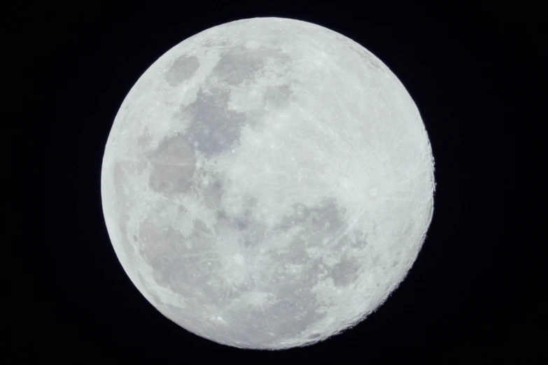 a full moon seen from the ground in the dark sky