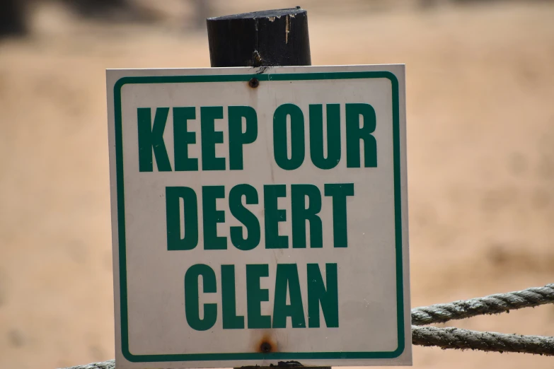 a sign on a pole that says keep our desert clean