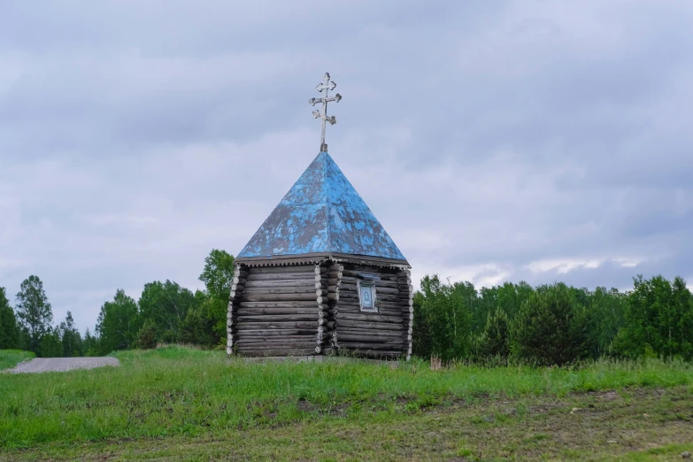 a wooden cabin with a blue roof on a green grass covered field