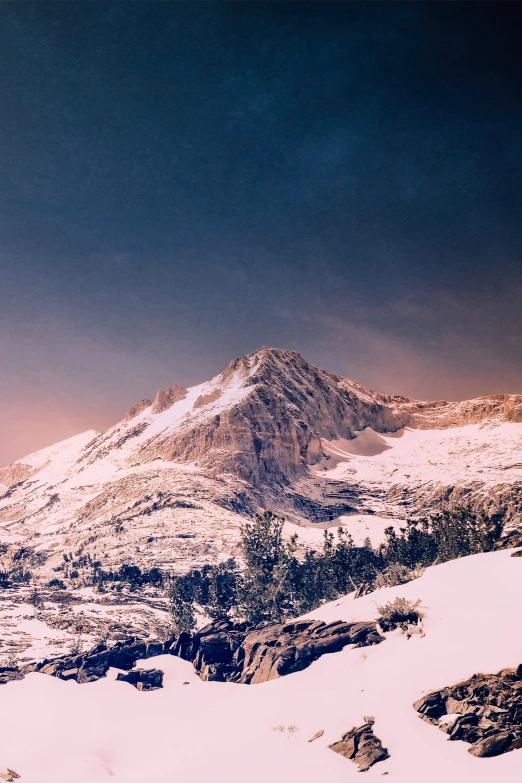 a mountain with snow covered mountains and evergreens on top