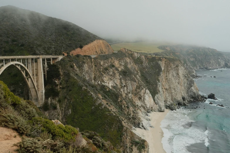 a road is seen passing over a bridge by the ocean