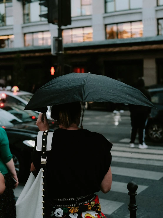 a woman holding an umbrella over her head as she walks down the street