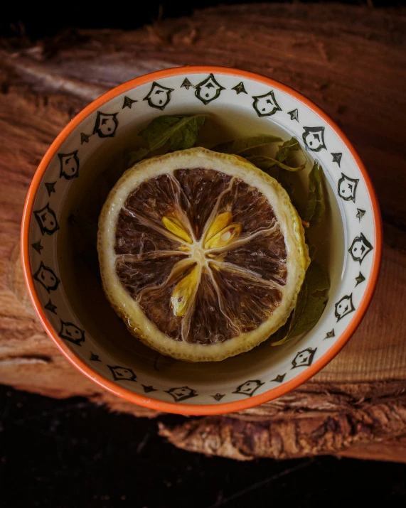 a bowl filled with a half orange and some green leaves