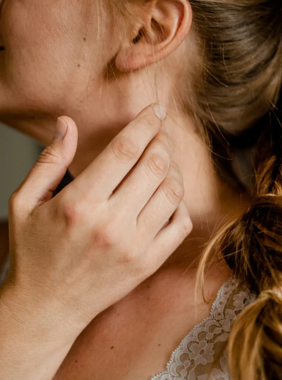 a woman has her hand on the side of her neck