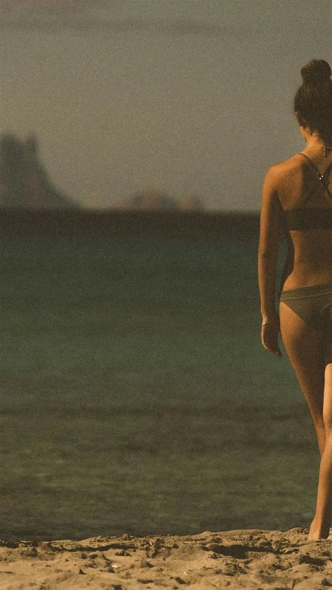 a woman in a bikini is standing on the beach