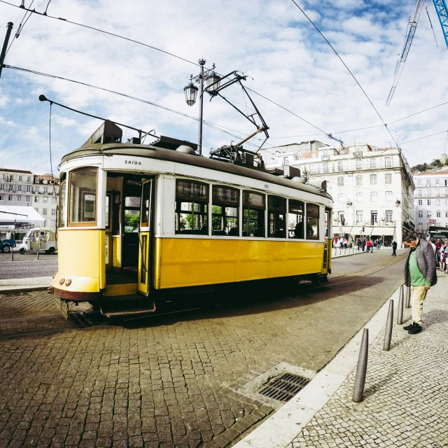 the yellow trolley is traveling down the street