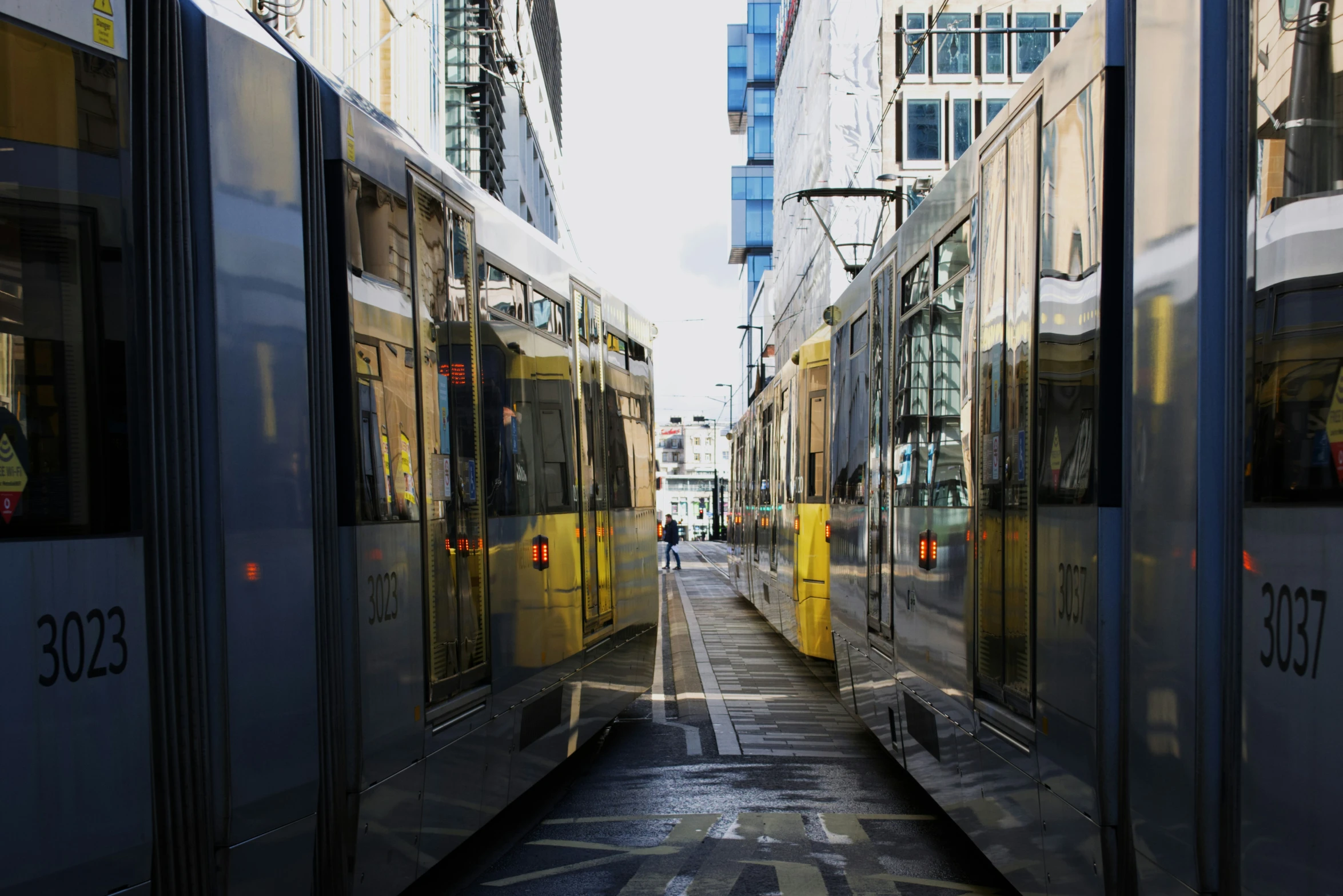 several city buses parked in a street with tall buildings