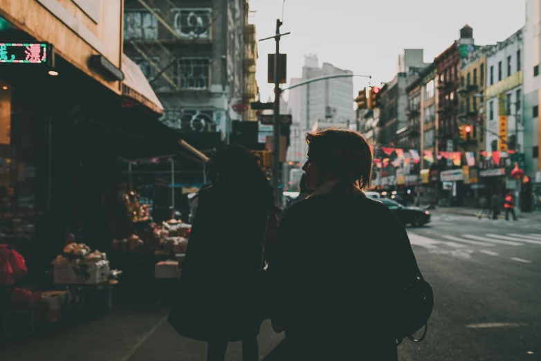 two people walk down the street as traffic lights go by