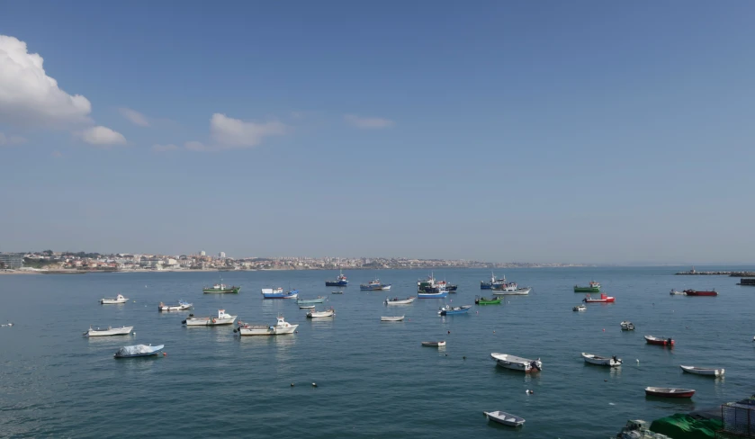 boats are floating on the ocean next to a large city