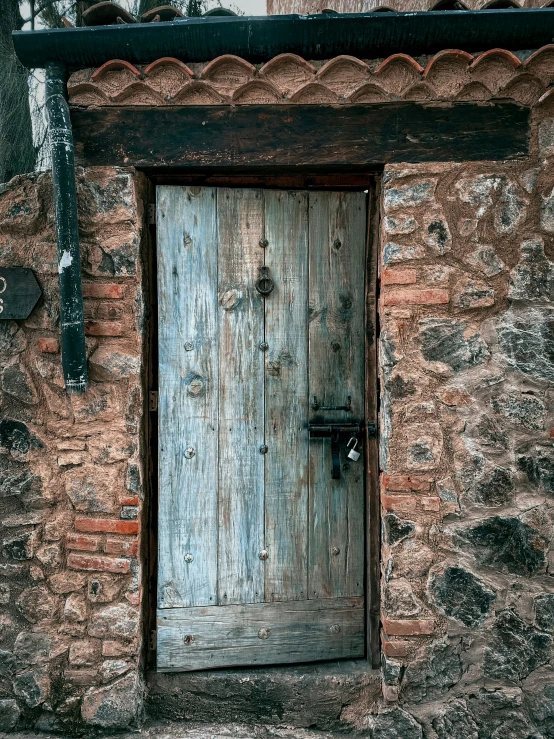 a brick wall with an old wooden door and small window