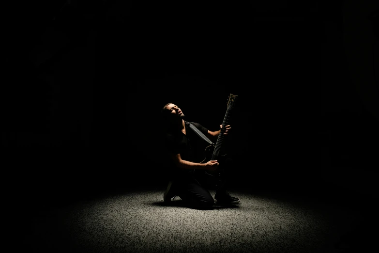 a man is sitting down and holding his guitar