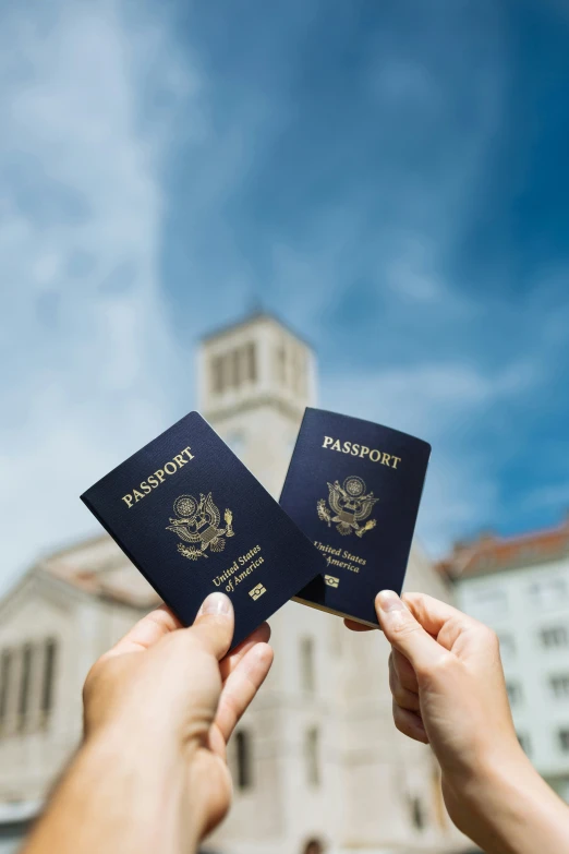 two people holding up some passports in front of a building