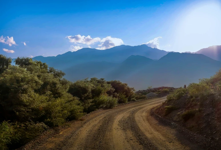 the sun shines brightly on a dirt road