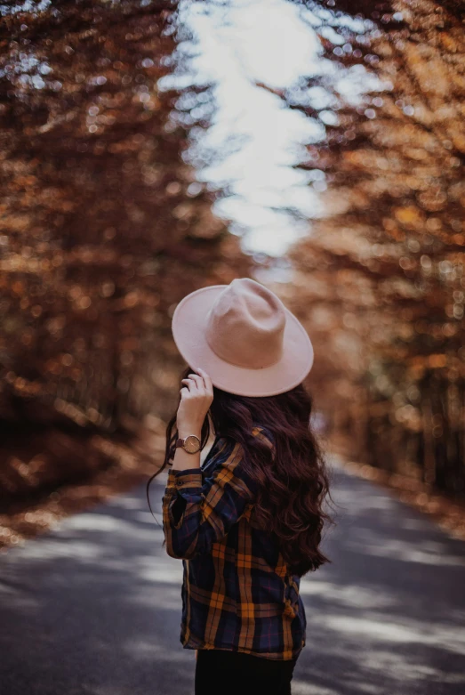 a young woman wearing a hat is holding her cellphone