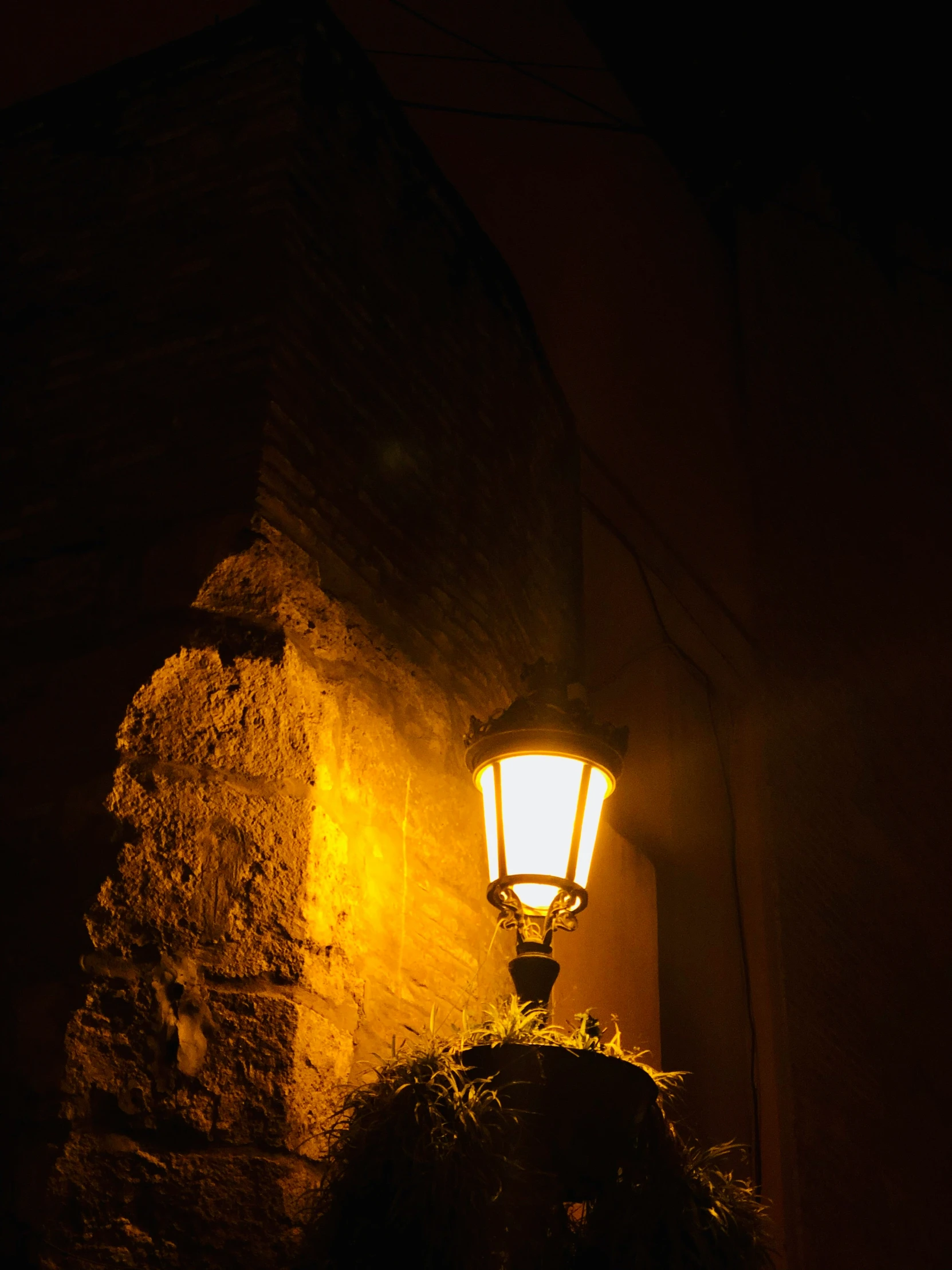 the lamp post is illuminated on the side of a building