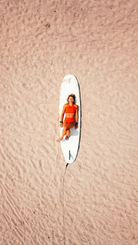 a woman laying on her stomach on top of a surf board