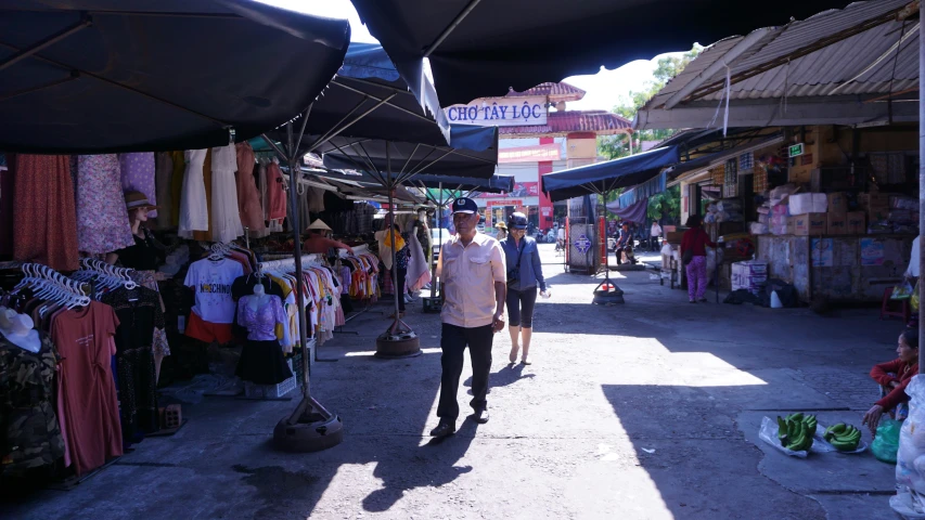 a man walking down the street in an alley with a market place on one side and stalls for people to shop on