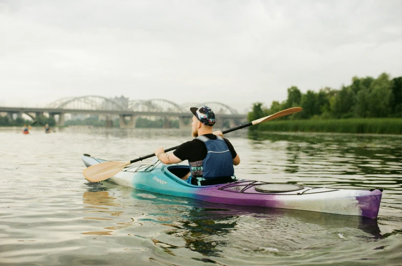 a man on a kayak in front of a bridge