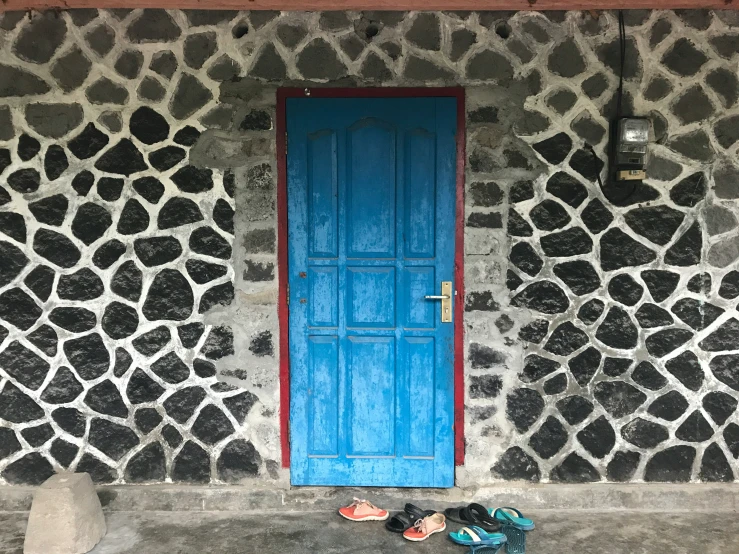 a blue door and red frame on a stone wall