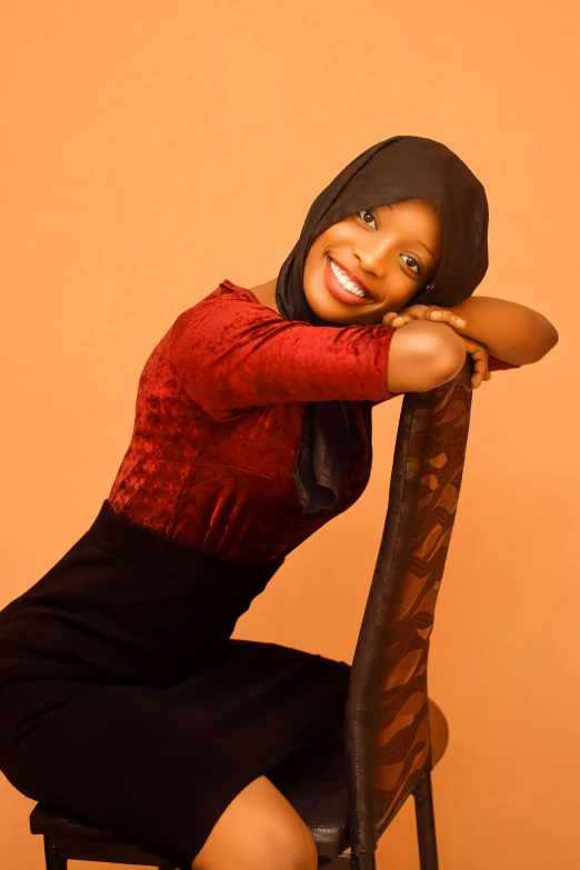 a woman posing on a chair in an orange background