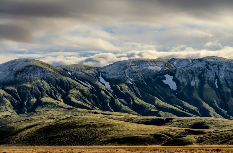 the mountains are covered with snow and green grass