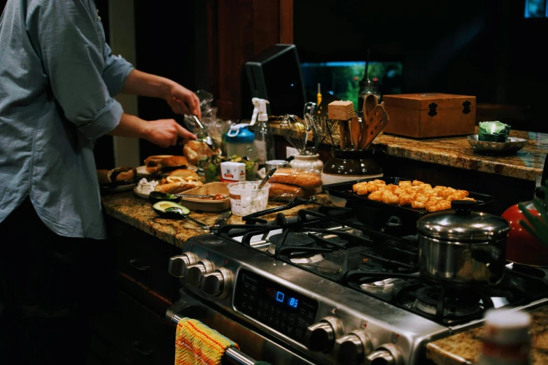 a man standing over a stove preparing food on it