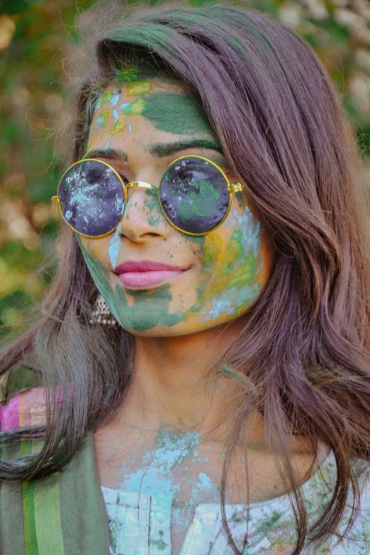 a young lady with dark hair and glasses covered in paint