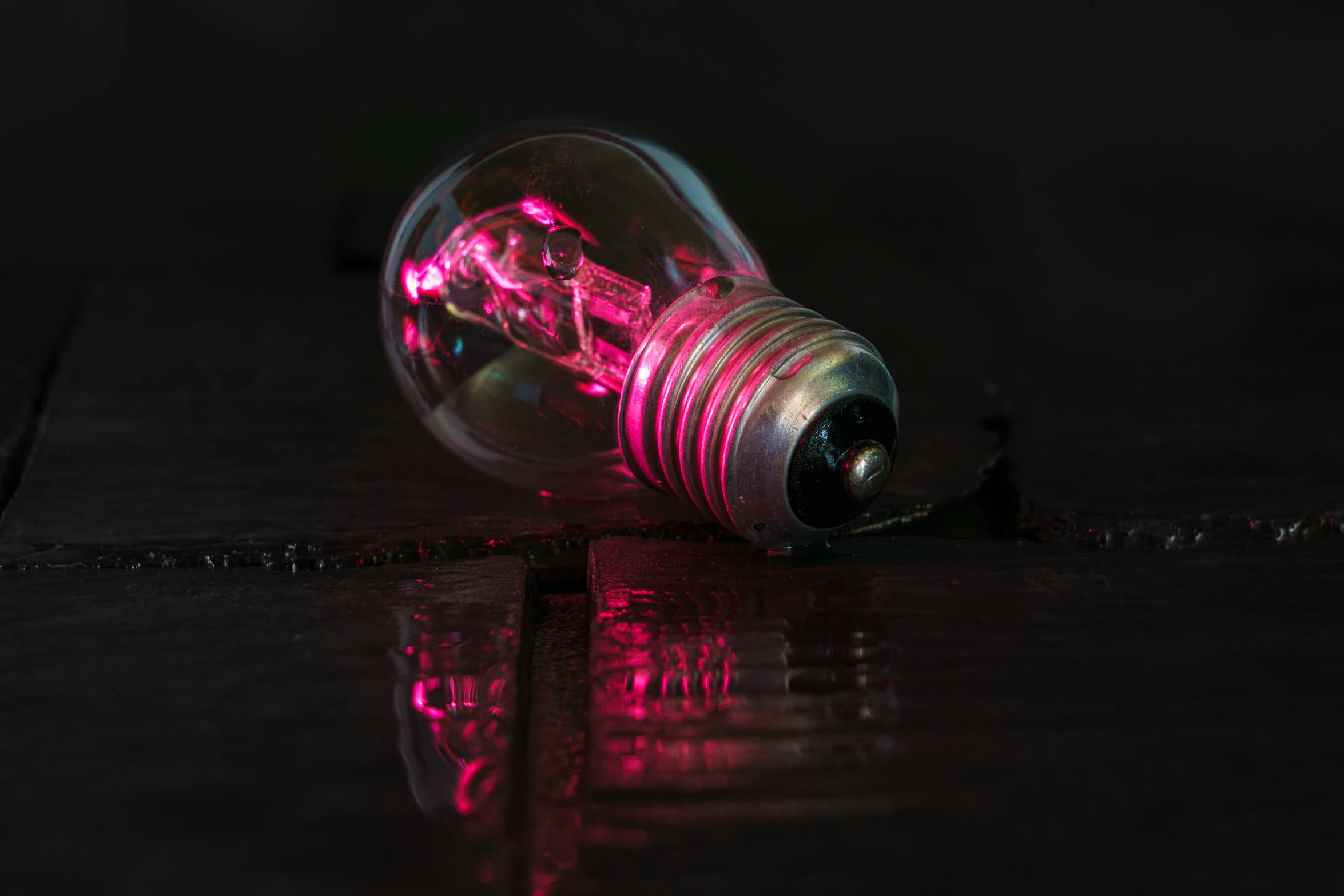 a pink light bulb in the dark on a floor