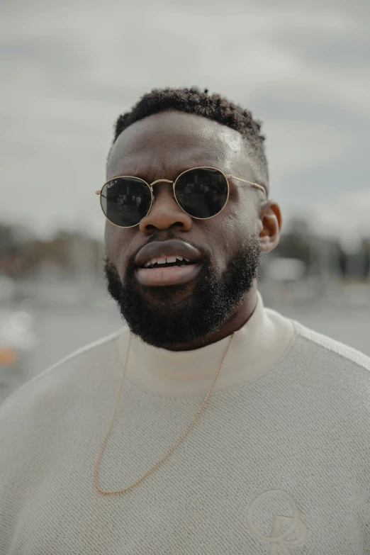 a man in shades and a sweater stares directly into the camera