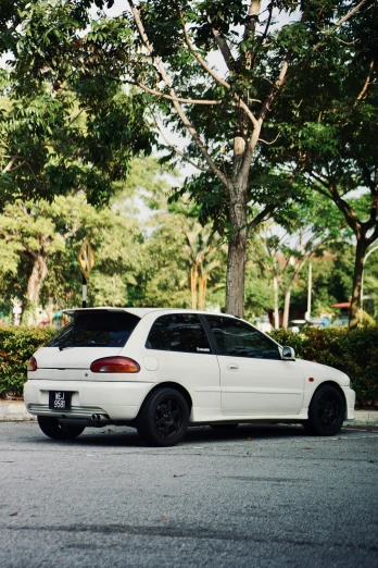 a white car sitting next to a tall tree