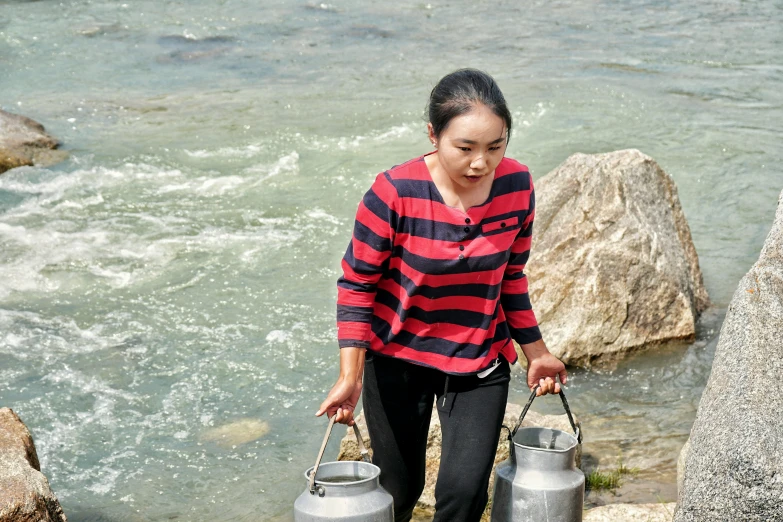 an asian woman stands next to two water pots