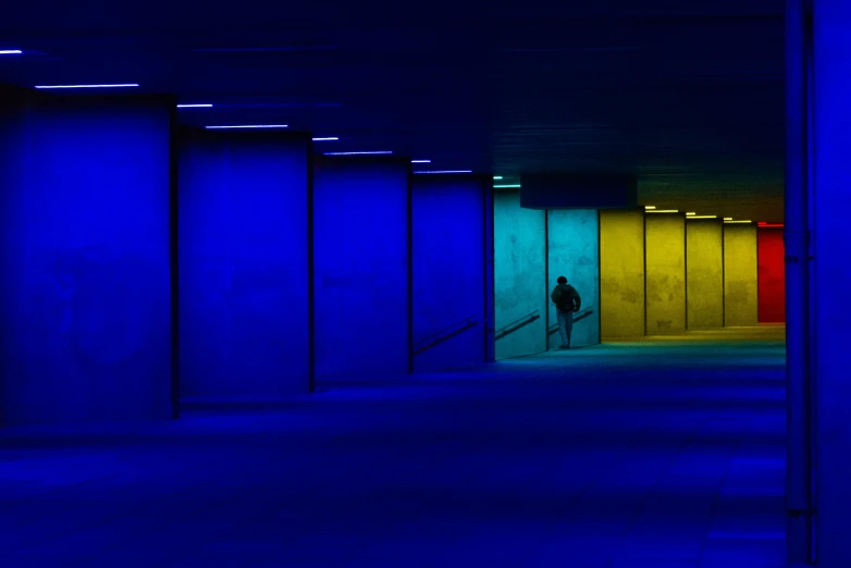 a man is walking past three brightly lit walls