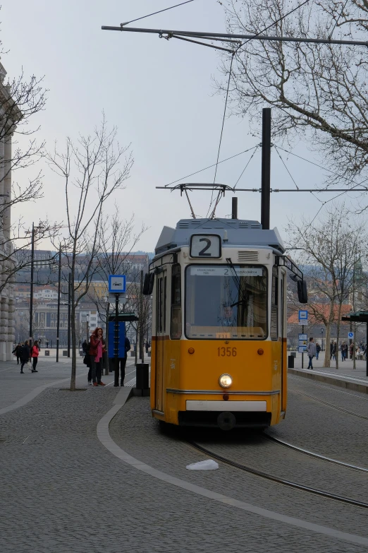 a yellow tram is pulling passengers to the platform