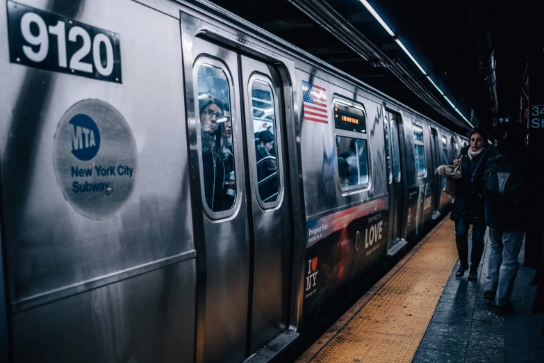 people walk on the platform next to a metro train