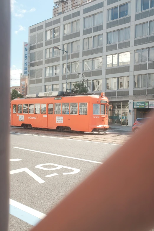 the street car is driving in front of the building