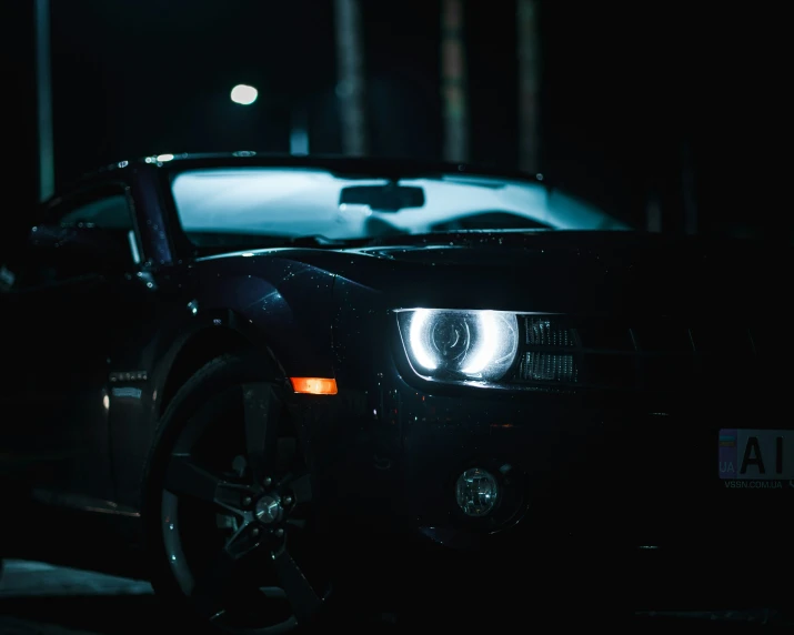a black sports car parked at a street intersection at night