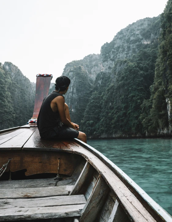 a man sitting on a boat with  on looking out over the water